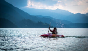 Pokhara, Nepal: Kayaking with splashes on red kayak on lake, Pokhara